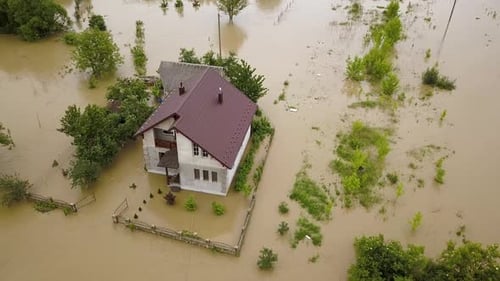 Aerial view of flooded house with dirty water all around it.