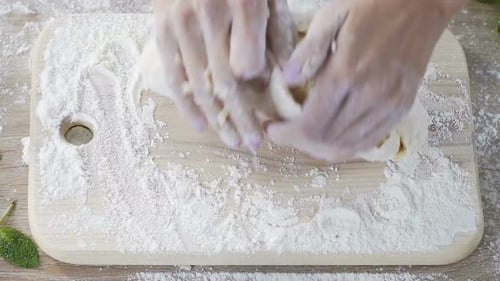 Bakery female worker diligently kneading dough before making bread portion