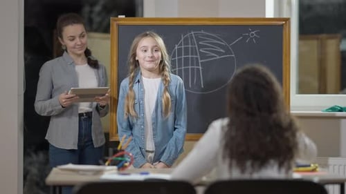 Child Giving Presentation in Classroom with Teacher