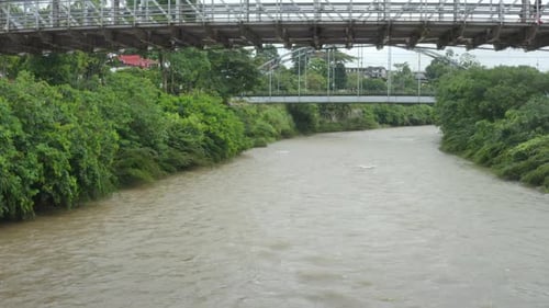 Moving over a large river with a brown coloration under a old bridge
