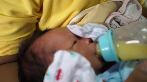 El recién nacido está tomando leche materna de un biberón, con una inyección a cámara lenta