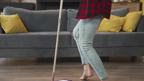 Mujer joven limpiando el suelo y bailando