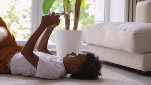 Child Lying on Floor Using Tablet at Home