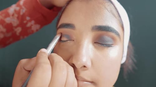 Close up of make up artist putting a eye shadow with make up brush on woman's eyes