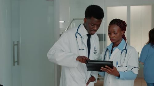 Doctors Reviewing Tablet Data in Hospital Setting