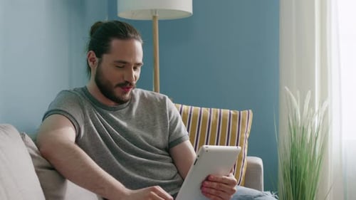 Young Adult Using Tablet for Video Call at Home