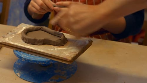 Mains d'un potier aidant une potière
