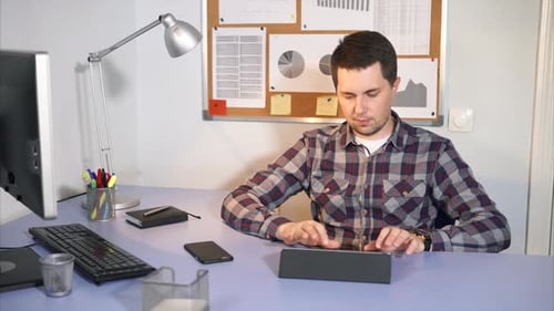 Un employé de bureau vérifie le courrier entrant sur la tablette qui se trouve dans son bureau.