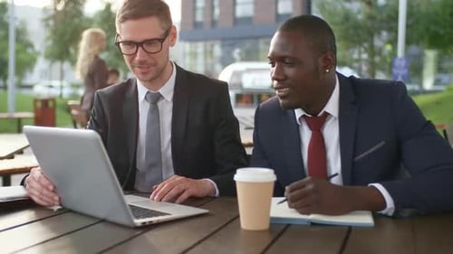 Multiethnic Businessmen Using Laptop Outdoors