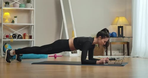Side View of Confident Strong Caucasian Woman in Plank Pose Looking in Laptop Screen. Wide Shot of
