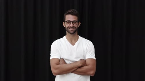 Smiling Man Adjusts Glasses in a Studio