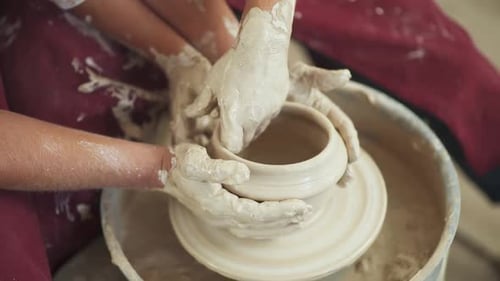 Craftsperson and Child Molding Clay on Pottery Wheel