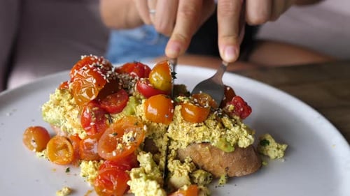 Person Cutting Into Tofu Scramble Toast With Avocado