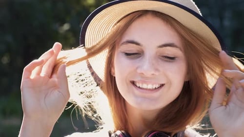 Portrait of pretty positive teenage girl with red hair wearing straw hat and pink