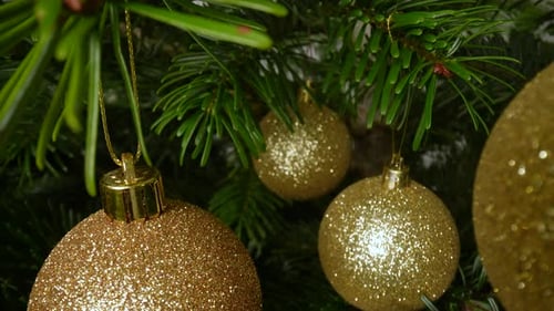 Sparkly Gold Baubles Hanging on Christmas Tree
