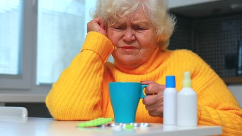 Senior Woman with Medicine and Mug at Table