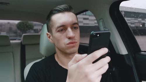 Man Sitting in Car Using his Smartphone