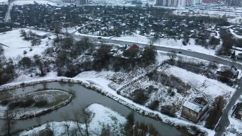 Flight over the river in a snow-covered city park. Aerial photography.