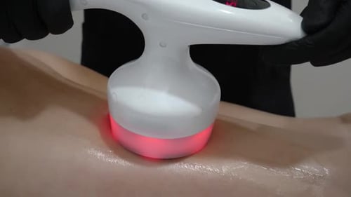 Medical Technician Operating Electronic Massage Tool on Back