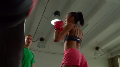 Young Woman Boxing With Punching Bag in Gym