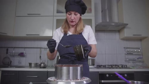 Woman Decorates Delicious Cake with Chocolate in Kitchen