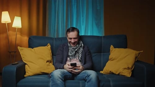 Man Relaxing on Sofa Using His Phone