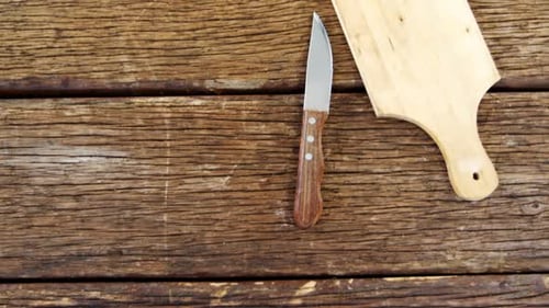 Knife and Cutting Board on Rustic Wood Table