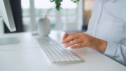Woman Typing on a White Keyboard at Desk