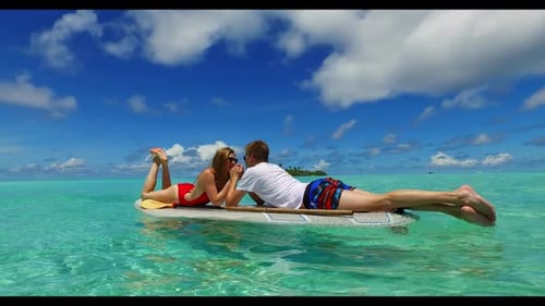 Guy and girl tanning on tranquil coastline beach vacation by blue lagoon and white sandy background