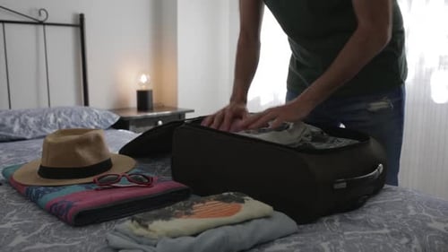 Man Packing Suitcase for Travel in Bedroom