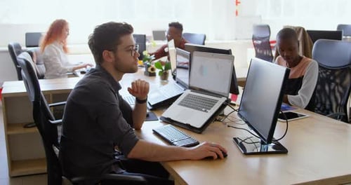 Side view of young cool mixed-race business team working at desk in a modern office 4k