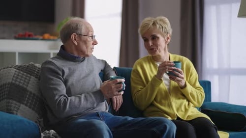 Senior Couple Drinking Coffee and Chatting at Home