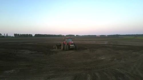 Red Tractor Cultivates Soil with Plough at Field Upper View