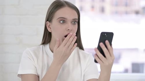 Surprised Woman Looking at Phone in Bright Room