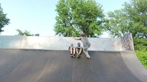 Man and woman watching their friend skateboarding on ramp at skatepark