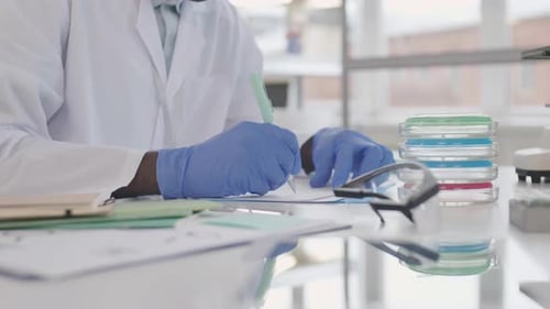 Scientist Writing at Lab Bench with Petri Dishes