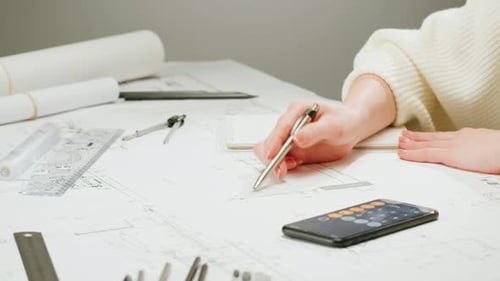 Architect Designer Counting on a Calculator Drawing Plan Blueprint Closeup