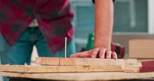 Close Up of Hammering a Nail Into Board A Carpenter Wearing a Red Flannel Shirt Jeans and Cloth