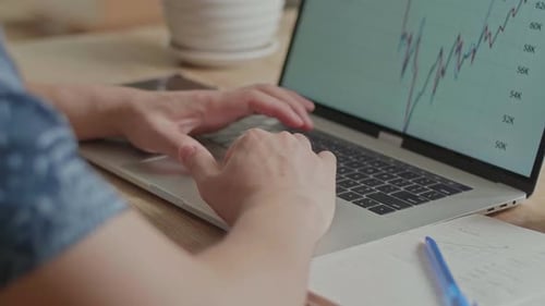 Hands Typing on Laptop Viewing Stock Charts