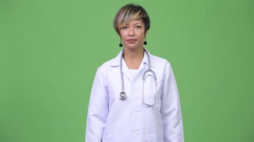 Confident Mature Doctor Poses Against Green Background