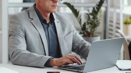 Midsection of Businessman Working on Laptop at Office Desk