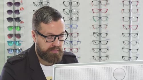 Mature Optometrist Working on a Computer at His Store