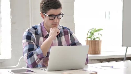 Young Adult Working on Laptop in Bright Office
