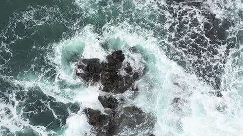 Aerial top view of rocks in the sea - Aerial video of majestic waves splashin
