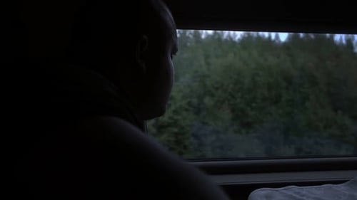 Side View of an Adult Man Sitting in a Train Carriage and Looking Out the Window