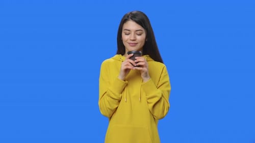 Smiling Woman Holding Coffee Against Blue Background