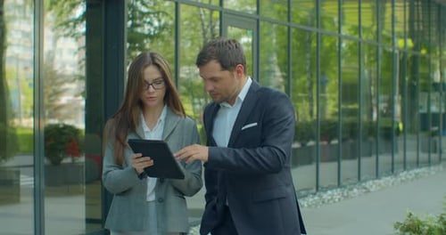Business People Going To Work with Digital Tablet on Street. Man and Woman Walking Near Office in