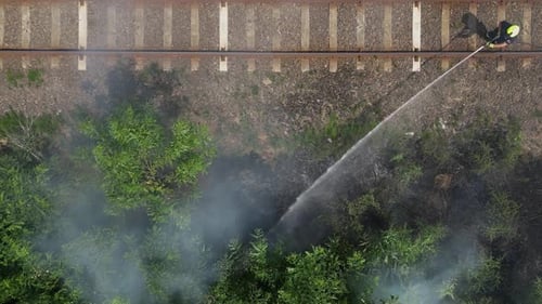 Firefighter Extinguishes Fire Near Train Tracks, Aerial View