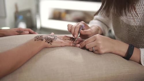 Doing Mehndi Art on Client's Hands.