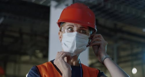 Woman Puts On Face Mask at Factory Workplace